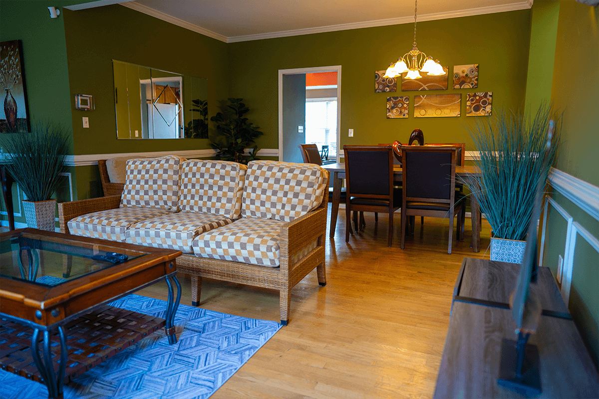 Wicker sofas and the dining table in the green common room at the Arnold home