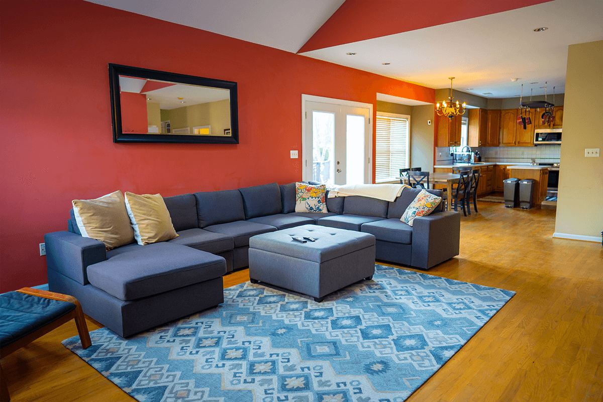 The red common room with a grey sectional, looking toward the kitchen, at the Arnold home