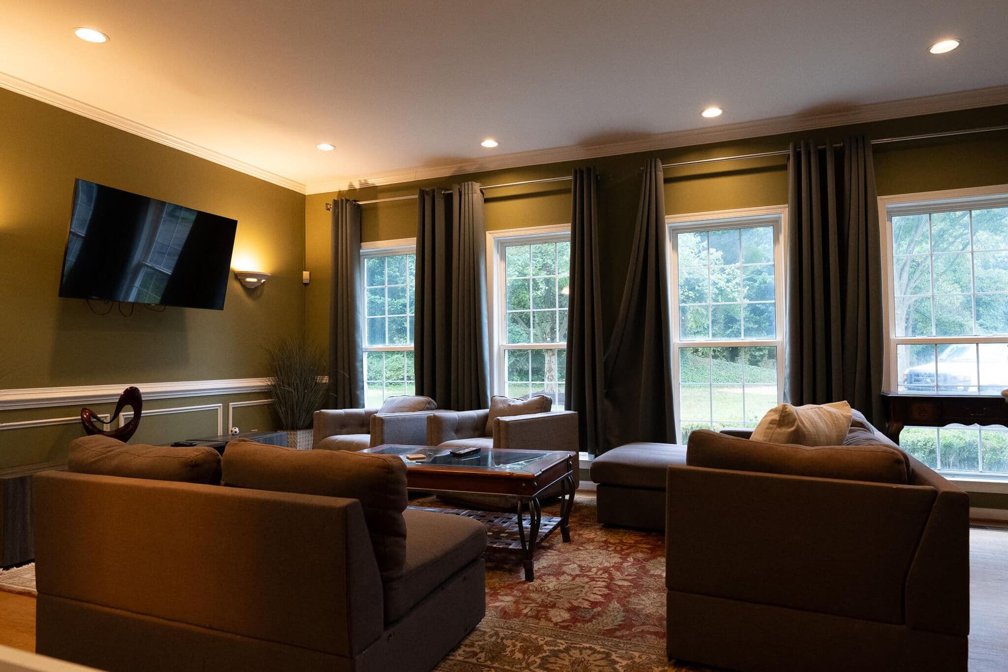 A second sitting room with brown sofas and a wall-mounted television at the Arnold home